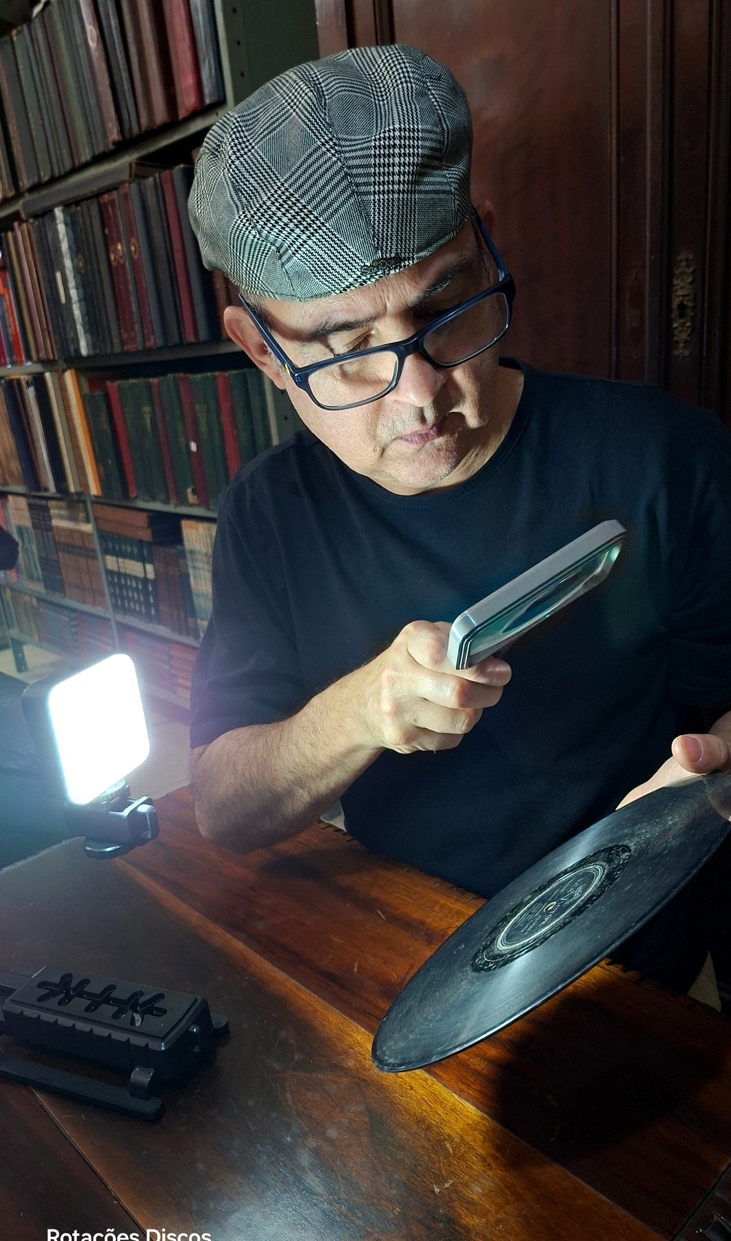 Alê Marcon avaliando um disco com lupa e luz lateral